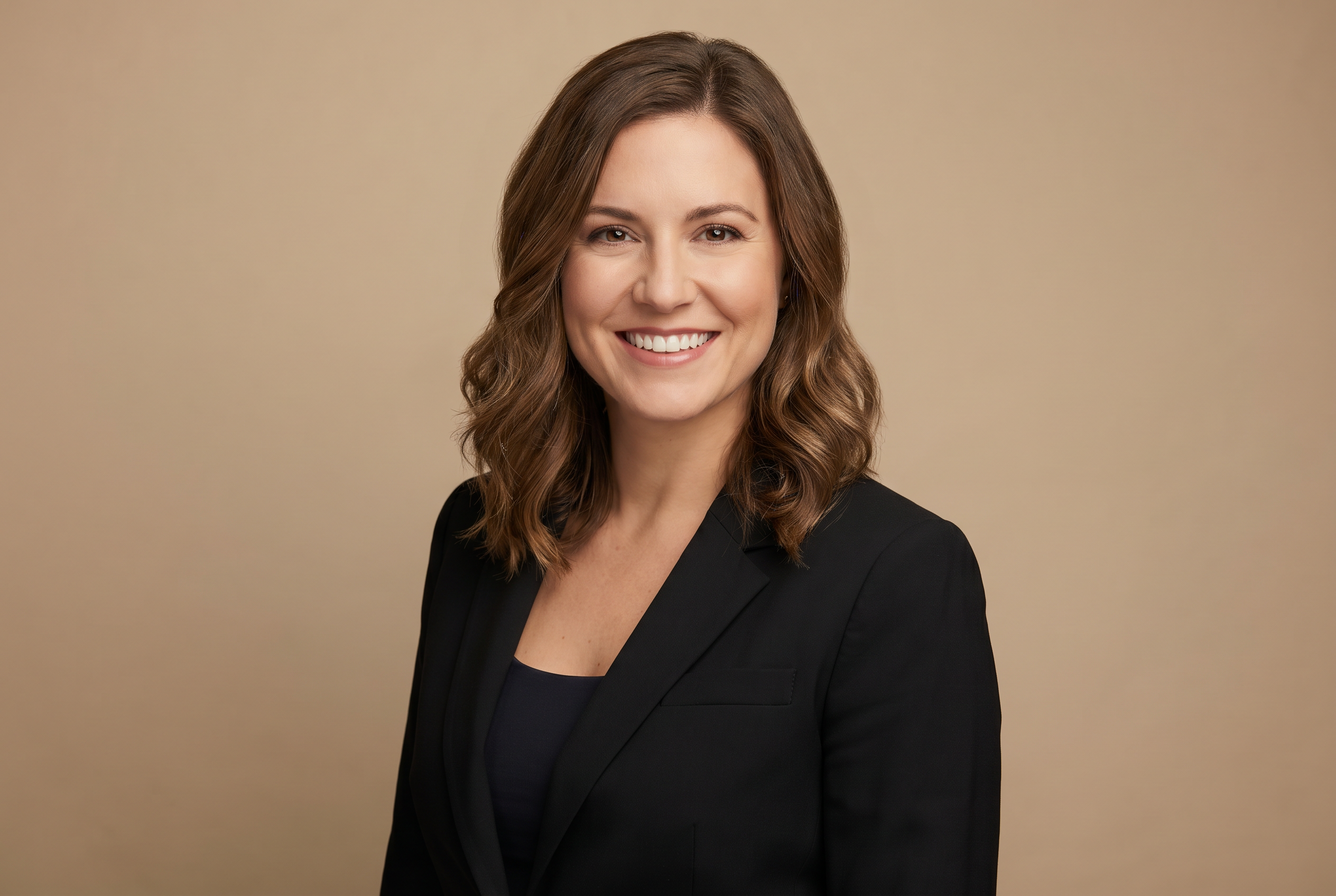 Professional headshot — confident woman in black blazer with warm studio lighting